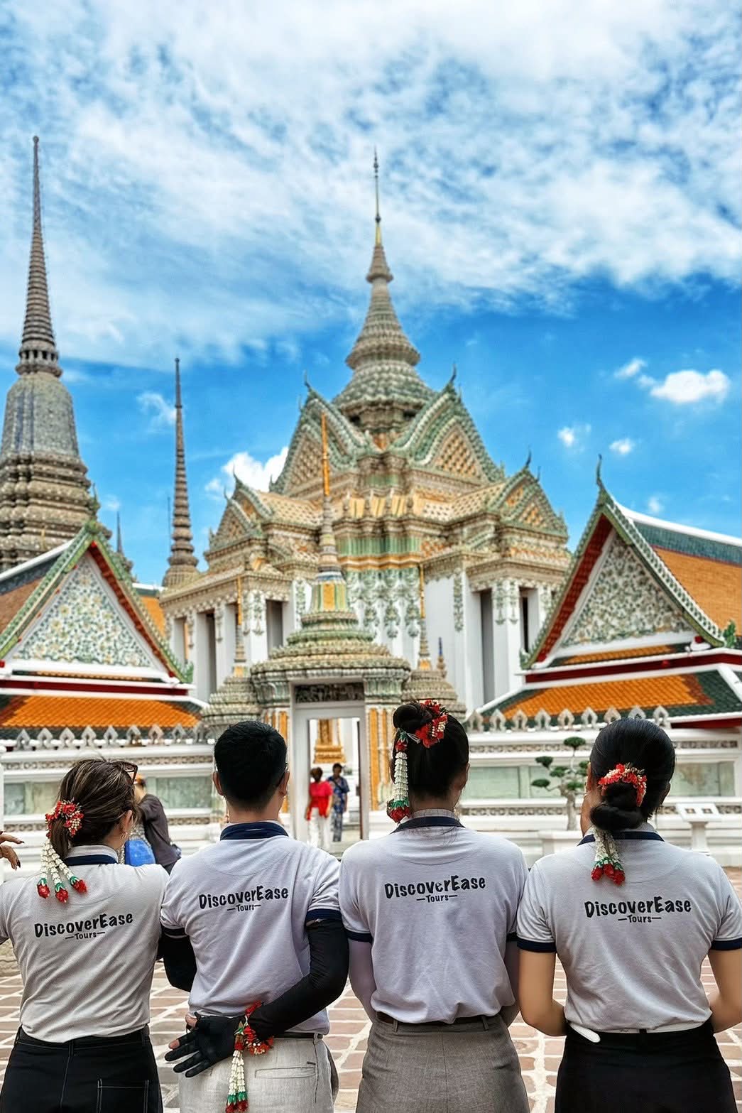 Four members of the DiscoverEase Tours team wearing company shirts in a temple courtyard